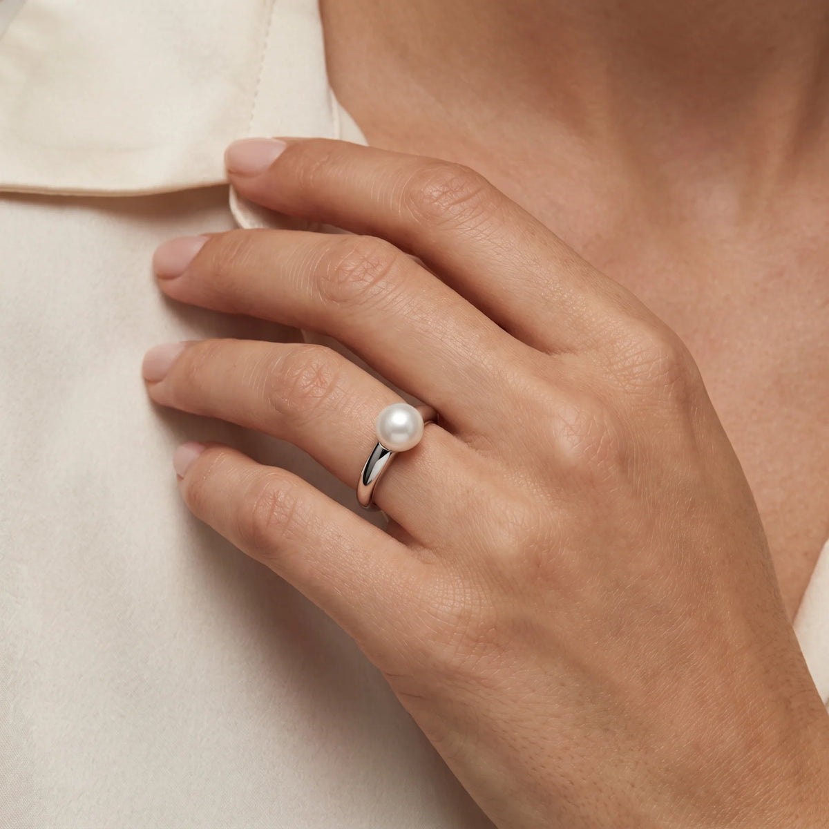 Damenring in 925er Silber rhodiniert mit Zuchtperle, an der Hand getragen (KI-generiert)