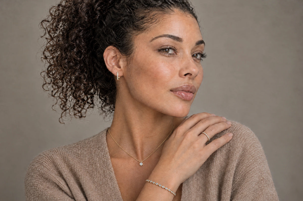 Frau mit Creole, Memoirering, Collier und Tennisarmband in Gold